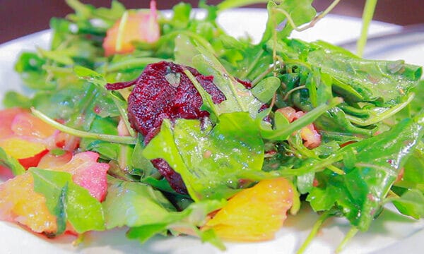 beet salad on a white plate, various greens make up the salad along with the beets