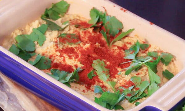 hummus dip in a blue glass dish, it is garnished with parsley