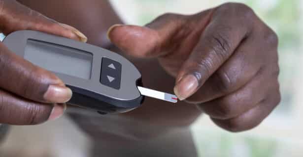 a man using a glucometer, his finger is touching the sensor attached to the glucometer
