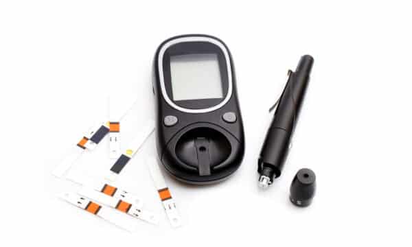 test strips and a lancet with the lid off lay next to a glucometer