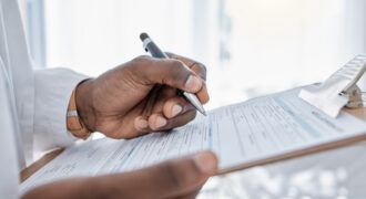 Healthcare provider holding a pen and completing a referral form for a patient